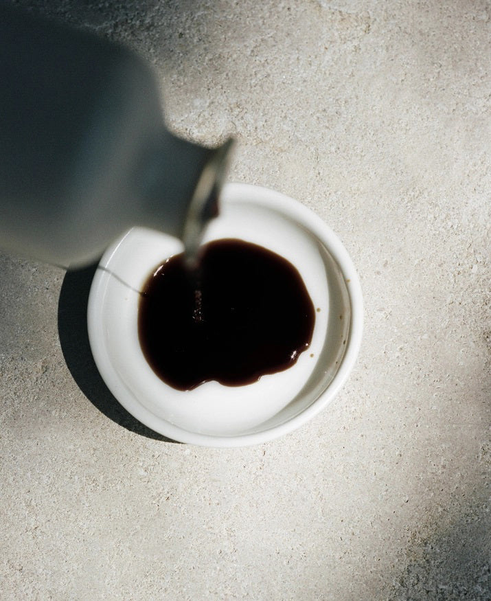 A minimalist bottle of LE MARKE - BALSAMIC VINEGAR, crafted from Trebbiano grapes, stands against a neutral background. The beige bottle, adorned with a wooden cork stopper and a label that reads &quot;LE MARKE Balsamic Vinegar 18 Year Barrel Aged Modena, Italy,&quot; exudes elegance and tradition.