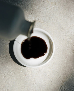 A minimalist bottle of LE MARKE - BALSAMIC VINEGAR, crafted from Trebbiano grapes, stands against a neutral background. The beige bottle, adorned with a wooden cork stopper and a label that reads "LE MARKE Balsamic Vinegar 18 Year Barrel Aged Modena, Italy," exudes elegance and tradition.