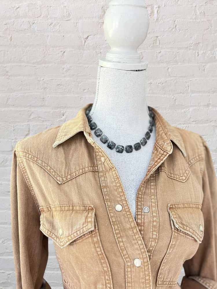 A mannequin displays a tan button-up denim shirt with chest pockets and an ANN LIGHTFOOT SQUARE LARVIKITE RAS DU COU NECKLACE 16″, featuring a sterling silver clasp, set against a white brick wall.
