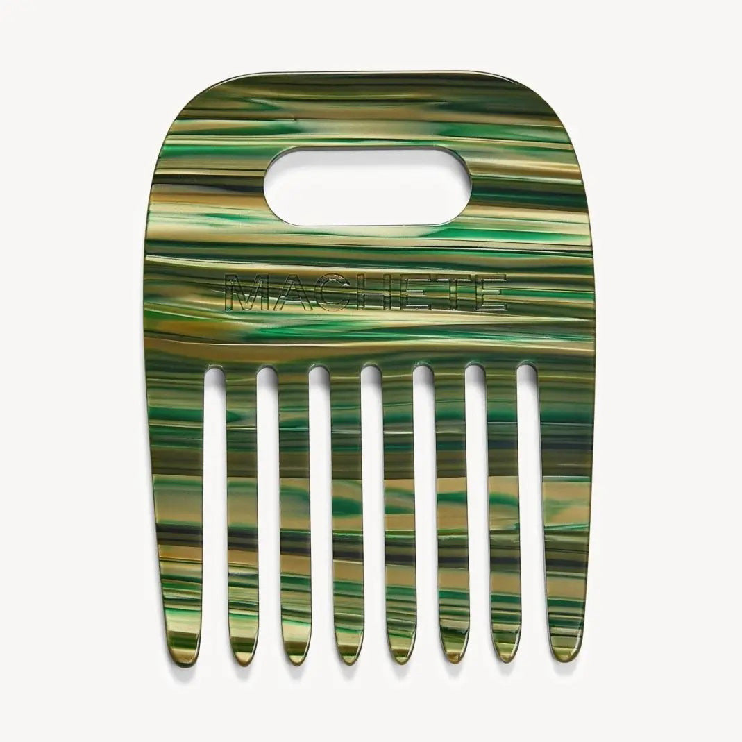 The MACHETE - NO. 4 COMB IN MEADOW is a wide-tooth comb made from Italian acetate with a marbled green, yellow, and brown finish, a rectangular handle slot, and "MACHETE" embossed on top—ideal for styling curly hair.