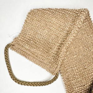 A close-up of the SMILE BOUTIQUES NATURAL ORGANIC JUTE BACK SCRUBBER, featuring a brown, woven jute design with a braided handle at one end and laid flat on a white background—this handmade bath accessory offers a sustainable upgrade to your shower routine.