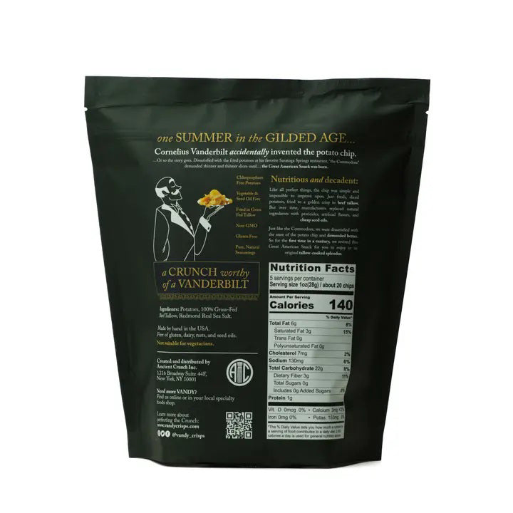 A black bag labeled &quot;ANCIENT CRUNCH - VANDY TRADITIONAL POTATO CHIPS&quot; stands upright with a stylish design, surrounded by a scattered pile of golden-brown potato chips in front of it.