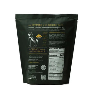 A black bag labeled "ANCIENT CRUNCH - VANDY TRADITIONAL POTATO CHIPS" stands upright with a stylish design, surrounded by a scattered pile of golden-brown potato chips in front of it.