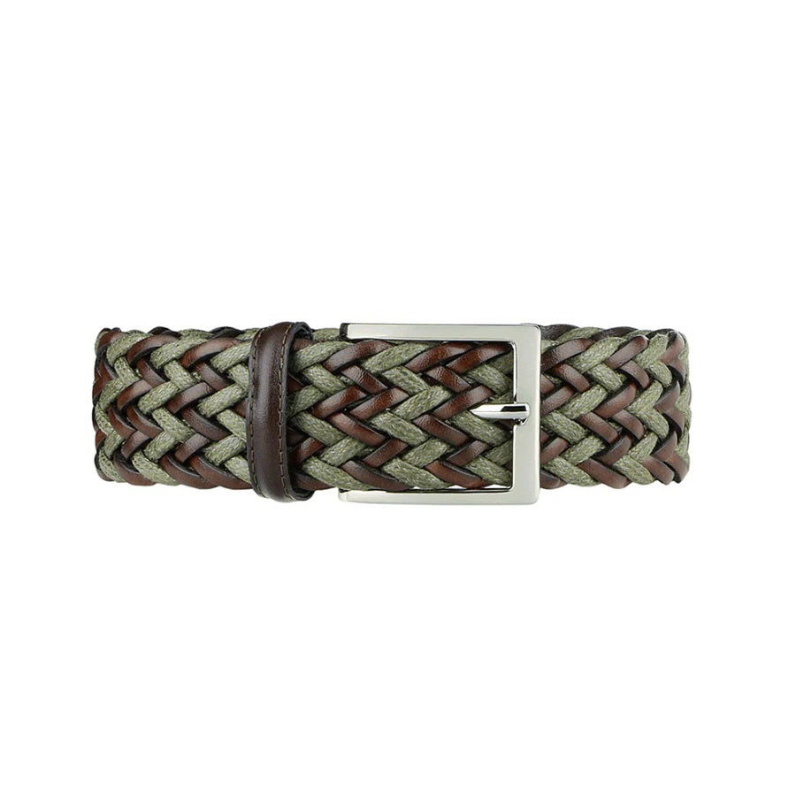 A person wears a light green shirt tucked into cream pants, hands in pockets, accessorized with the ATHISON braided leather and linen belt in dark brown and olive. Lush greenery fills the background.