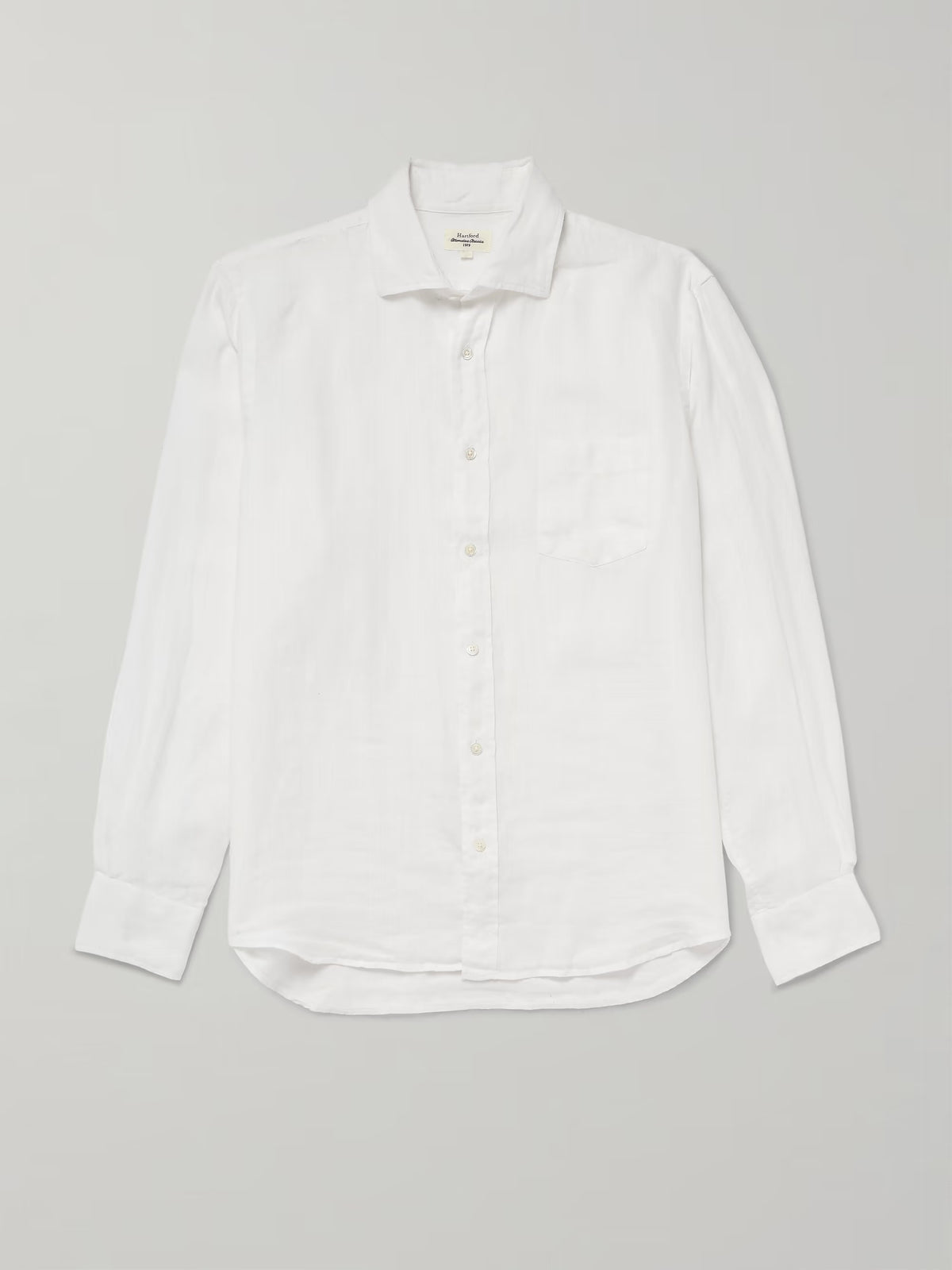 The HARTFORD - PAUL LINEN SHIRT IN WHITE by HARTFORD is a long-sleeved, button-up men's shirt crafted from premium European Flax linen, featuring a collar and single chest pocket, shown flat on a plain light grey background.