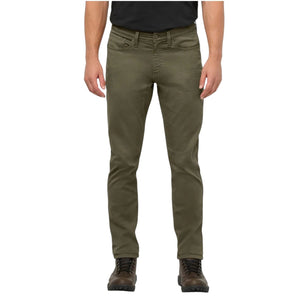 A person stands facing away from the camera against a plain background, wearing DUER - NO SWEAT ATHLETIC TAPER PANTS IN KELP paired with brown shoes.