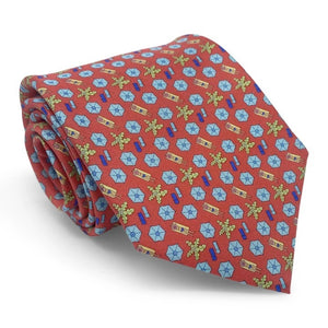 A rolled-up red necktie featuring a repeating pattern of pink beach umbrellas, yellow-green palm trees, and blue beach towels, the Peter-Blair Sunscreen Silk Tie by Bird Dog Bay is handmade in New York and finished with the signature Peter-Blair woven label.