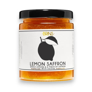 A jar labeled “BRINS - LEMON SAFFRON MARMALADE” from BRINS, garnished with a lemon slice, sits against a light beige background. The jar holds a vibrant yellow marmalade crafted from whole fresh lemons and infused with aromatic saffron for a bright, floral flavor.