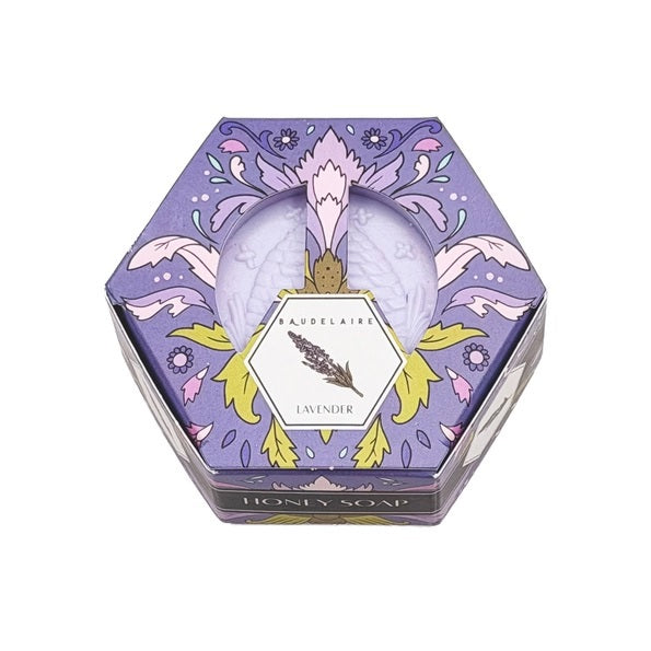 Hexagonal BAUDELAIRE - LAVENDER HONEY SOAP 3.5 OZ bars, each in decorative, colorful BAUDELAIRE-branded hex boxes, are arranged in a honeycomb pattern on a white surface. The soaps display unique designs and vibrant colors, with some unwrapped to reveal the luxurious triple-milled texture and enticing lavender honey fragrance.