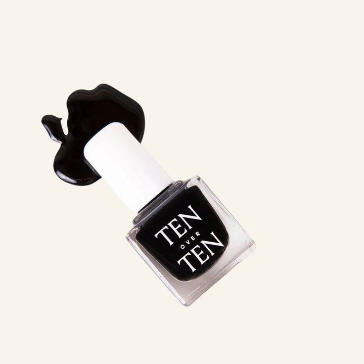 A glass bottle of TENOVERTEN - NAIL POLISH from the brand TEN OVER TEN, featuring a white cap and a dusty pink nail color. The front label displays "TEN OVER TEN" in white uppercase letters. This vegan, eight-free formula ensures both beauty and peace of mind. The background is plain and light-colored.