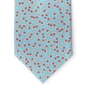 A rolled-up aqua silk tie by Bird Dog Bay, the Peter-Blair Spike Printed style, featuring a floral print in white, pink, and green.