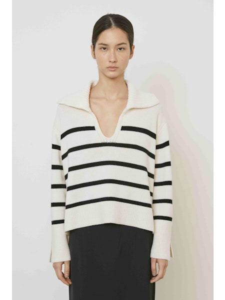 A woman with straight dark hair models the MEIMEIJ STRIPE SWEATER—a cream sweater with black horizontal stripes and a large collar—paired with a plain black skirt, standing against a white background.