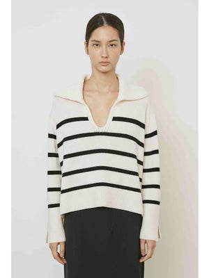 A woman with straight dark hair models the MEIMEIJ STRIPE SWEATER—a cream sweater with black horizontal stripes and a large collar—paired with a plain black skirt, standing against a white background.