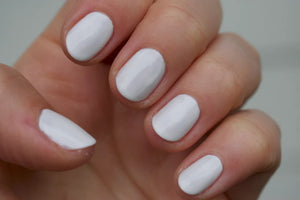 A glass bottle of TENOVERTEN - NAIL POLISH from the brand TEN OVER TEN, featuring a white cap and a dusty pink nail color. The front label displays "TEN OVER TEN" in white uppercase letters. This vegan, eight-free formula ensures both beauty and peace of mind. The background is plain and light-colored.