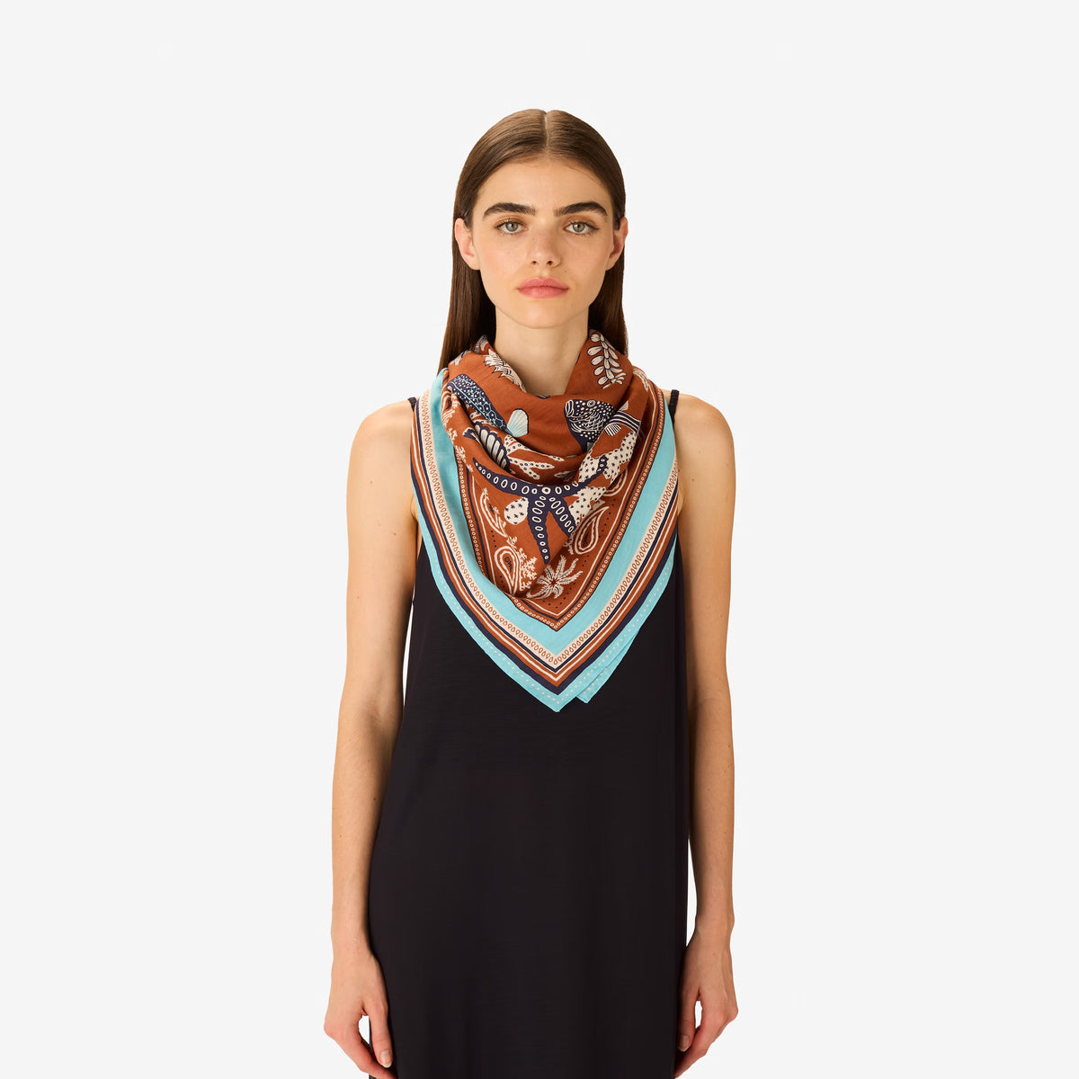 The INOUI EDITIONS - NEPTUNE SCARF IN GOLDEN BROWN by INOUI features detailed blue and white tropical fish, seaweed, shells, and coral on a brown background with an intricate blue, white, and brown border in cotton silk.
