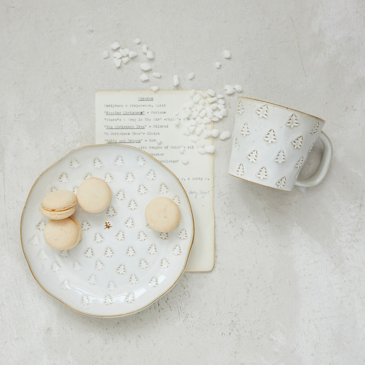 Creative Co-op DEBOSSED STONEWARE MUG WITH GOLD RIM AND TREE, matching creamer, and tree-shaped plate, all featuring a debossed tree pattern and gold rims, displayed with Christmas ornaments and small cookies as festive holiday drinkware.