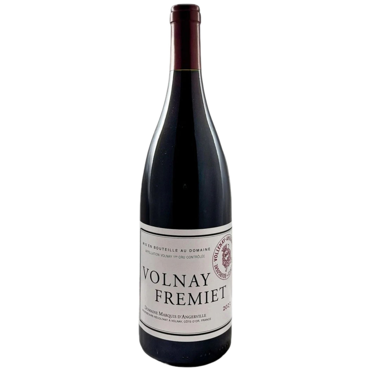 A bottle of MARQUIS D’ANGERVILLE VOLNAY 1ER CRU ‘FREMIET’ 2017 with a white label sits next to a glass of red wine on a white table.