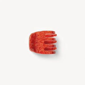 The MACHETE - MINI HAIR CLAW IN POPPY, a handcrafted marbled red claw clip with three prongs, made from Italian acetate, is displayed on a plain white background.