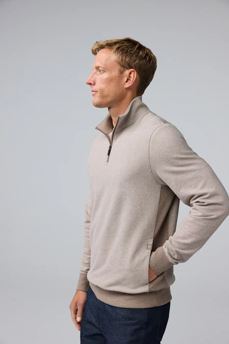A man wearing a tan Mack Weldon ACE QUARTER ZIP French terry pullover with ribbed cuffs and hem.