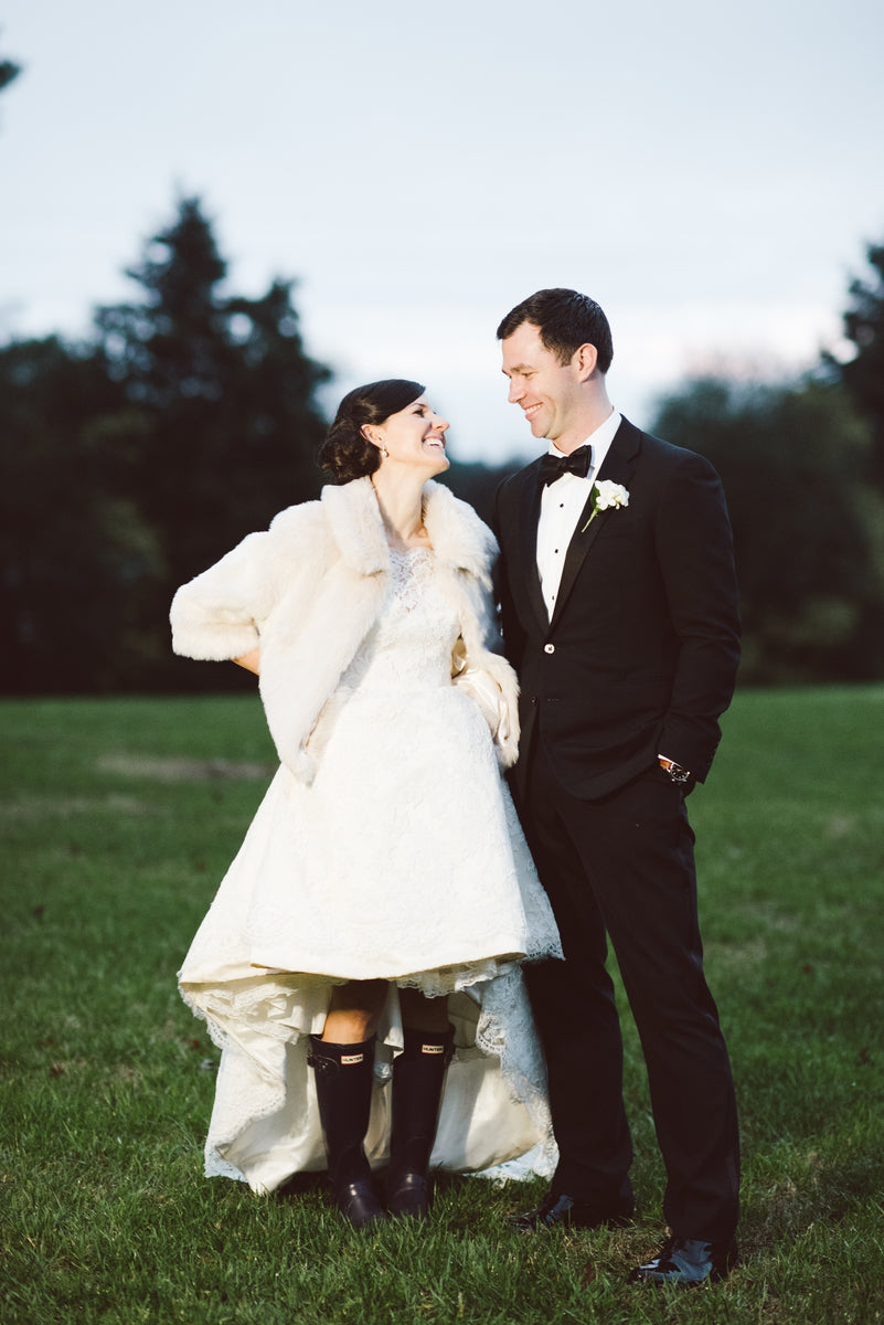 Wedding couple standing on a grassy field with trees in the background