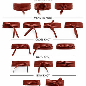 An ADA - LEATHER WRAP BELT IN MALBEC, a wide, deep red leather wrap belt worn over a light-colored dress as a versatile accessory.