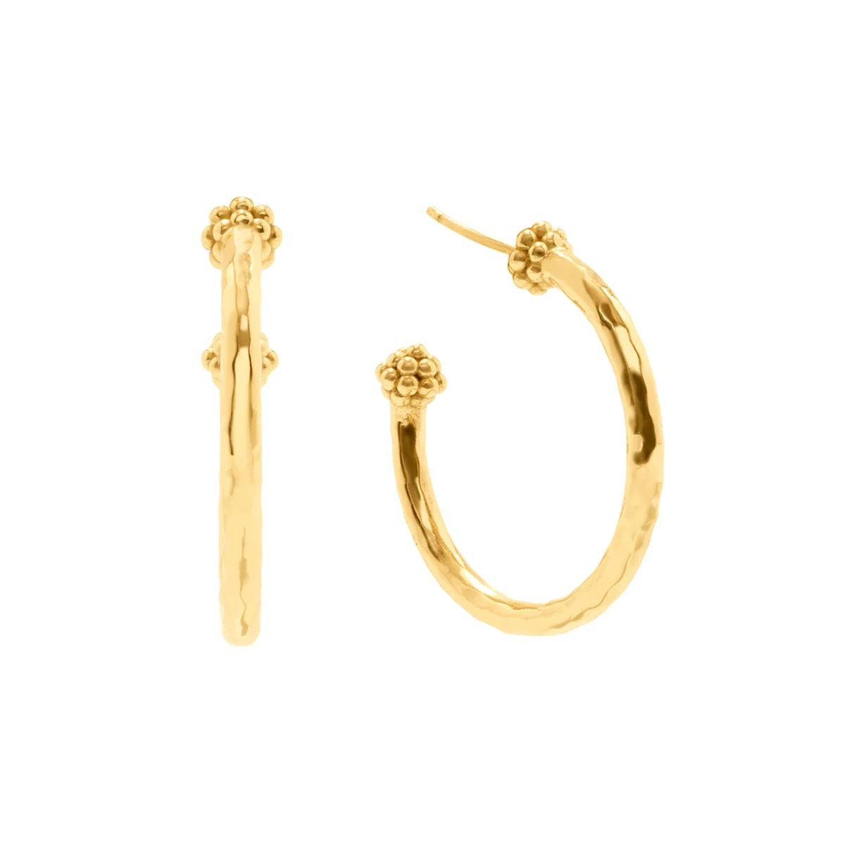 A woman with curly hair wears CAPUCINE DE WULF’s Berry Slice Hoop Earrings—a pair of hammered gold hoops—along with a chunky gold chain necklace. With her eyes closed and a serene expression, she poses against a softly blurred background, showcasing her appreciation for handmade jewelry.