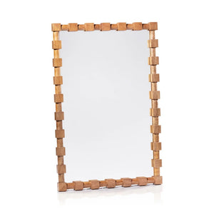 The ZODAX CADIER MANGO WOOD WALL MIRROR with a rectangular frame hangs on a textured gray wall above a wooden table displaying a potted plant, framed photo, books, and decor.