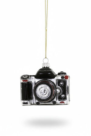 A black and silver GLASS CAMERA ORNAMENT by CODY FOSTER measuring 2.5 x 2 x 2.5 inches, hanging from a gold string.
