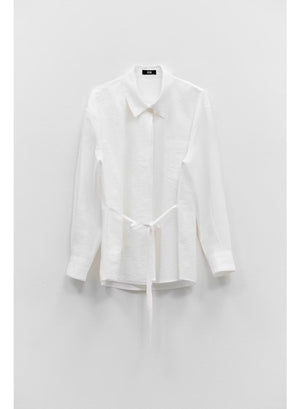The ELEH LONG SLEEVE SHIRT WITH TIES by ELEH, crafted from a white Italian cotton blend, hangs neatly against a plain white wall. Featuring a collar and waist tie detail, this modern button-down silhouette is perfect for any occasion.
