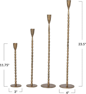 The CREATIVE COOP CAST IRON TAPER HOLDER IN BRASS FINISH, LARGE, features a tall, slender design with a textured segmented stem and round base, perfect for displaying a single taper candle.