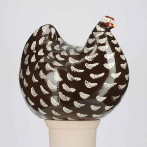A LES CERAMIQUES DE LUSSAN large ceramic French pullet in black spotted white stands on a light-colored cylindrical base against a plain background.