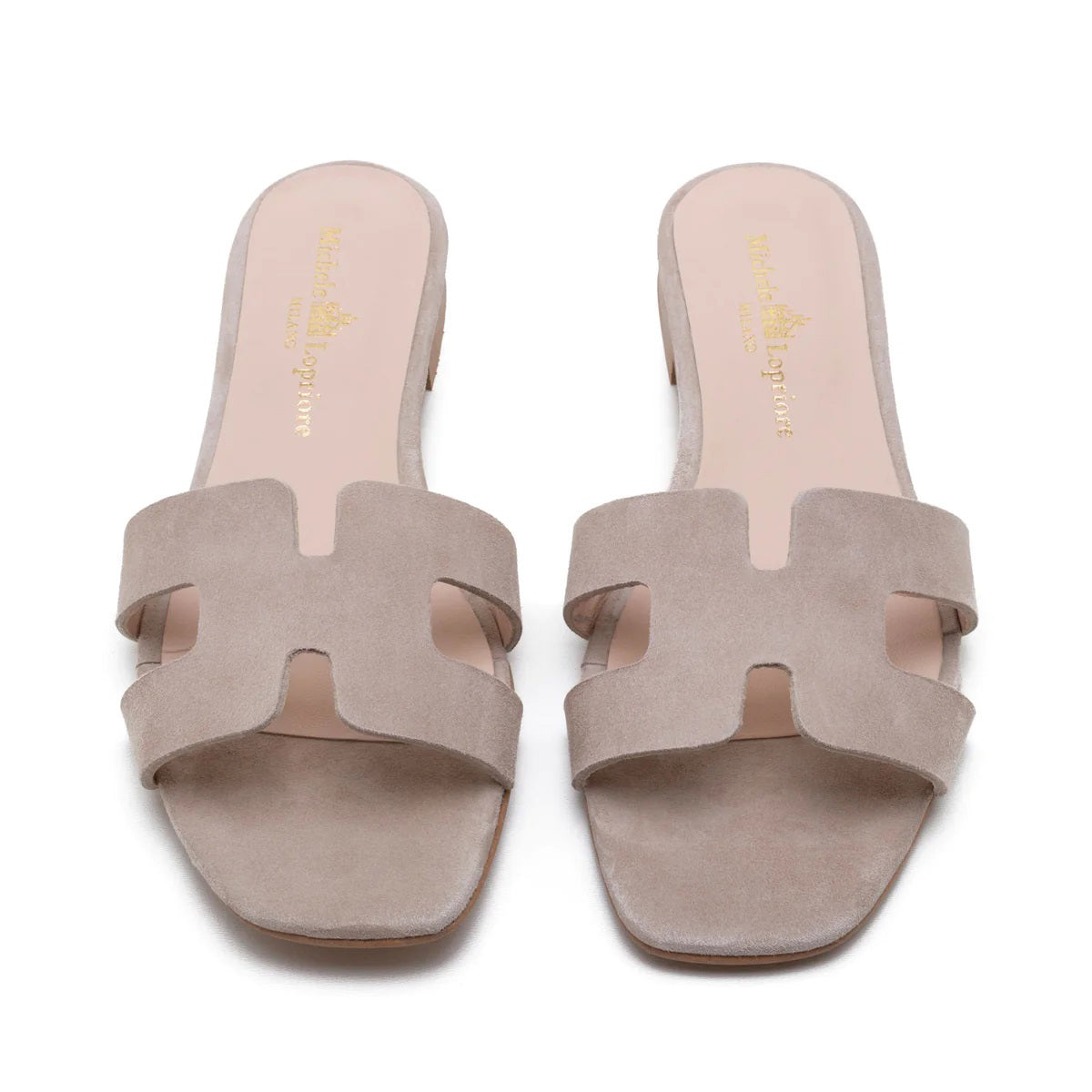 The image depicts the MICHELE LOPRIORE - H SLIDE, a single brown leather slide sandal with an open-toe design. The upper features two wide straps with geometric cutouts. The thin sole appears to be made of light brown wood-like material. Made in Italy by MICHELE LOPRIORE, the sandal is displayed against a plain white background.