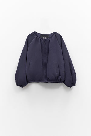 A person models the ELEH NYLON BOMBER JACKET, styled oversized with a matching mini skirt, black ankle boots, and large sunglasses against a plain white background. Brand: ELEH.