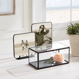 The NAPA HOME AND GARDEN - ARWEN RECTANGULAR BOX is a sleek glass and brass piece with a metal frame, hinged lid, and circular handle; perfect for storing mementos and beautifully displayed on a white background.