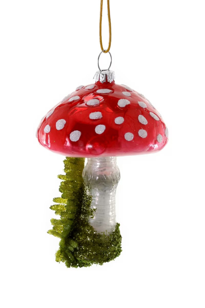 The HIGH GROVE MUSHROOM ORNAMENT by CODY FOSTER hangs gracefully, featuring a captivating design of a red mushroom with white spots. Its stalk, embellished with a textured green spiral motif, brings height and elegance to the festive decor.