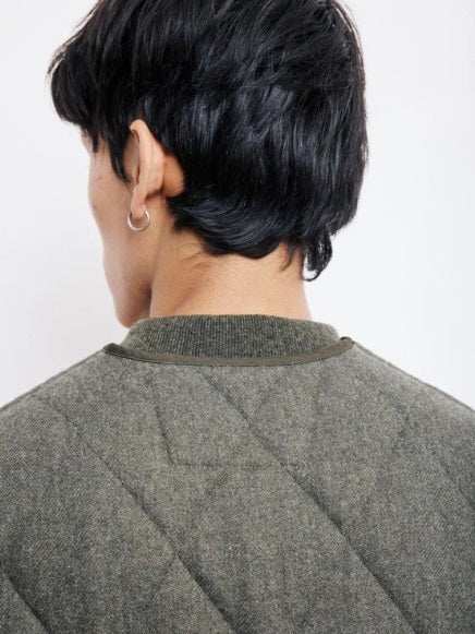 A person with short black hair, wearing a silver hoop earring and the HARTFORD - VINCE Wool Flannel Vest in Army, is shown from the back against a plain white background.