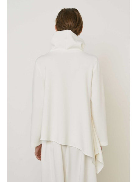 A person with brown hair faces away wearing the MEIMEIJ ASYMMETRICAL COWLNECK TOP in lightweight scuba fabric, featuring an asymmetrical hem, paired with matching white bottoms, against a plain white background.