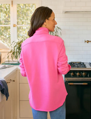 A woman with wavy brown hair wears the FRANK & EILEEN EILEEN Relaxed Sweatshirt Button Up in Lotus, featuring white buttons and a chest pocket, standing indoors with part of her face visible.