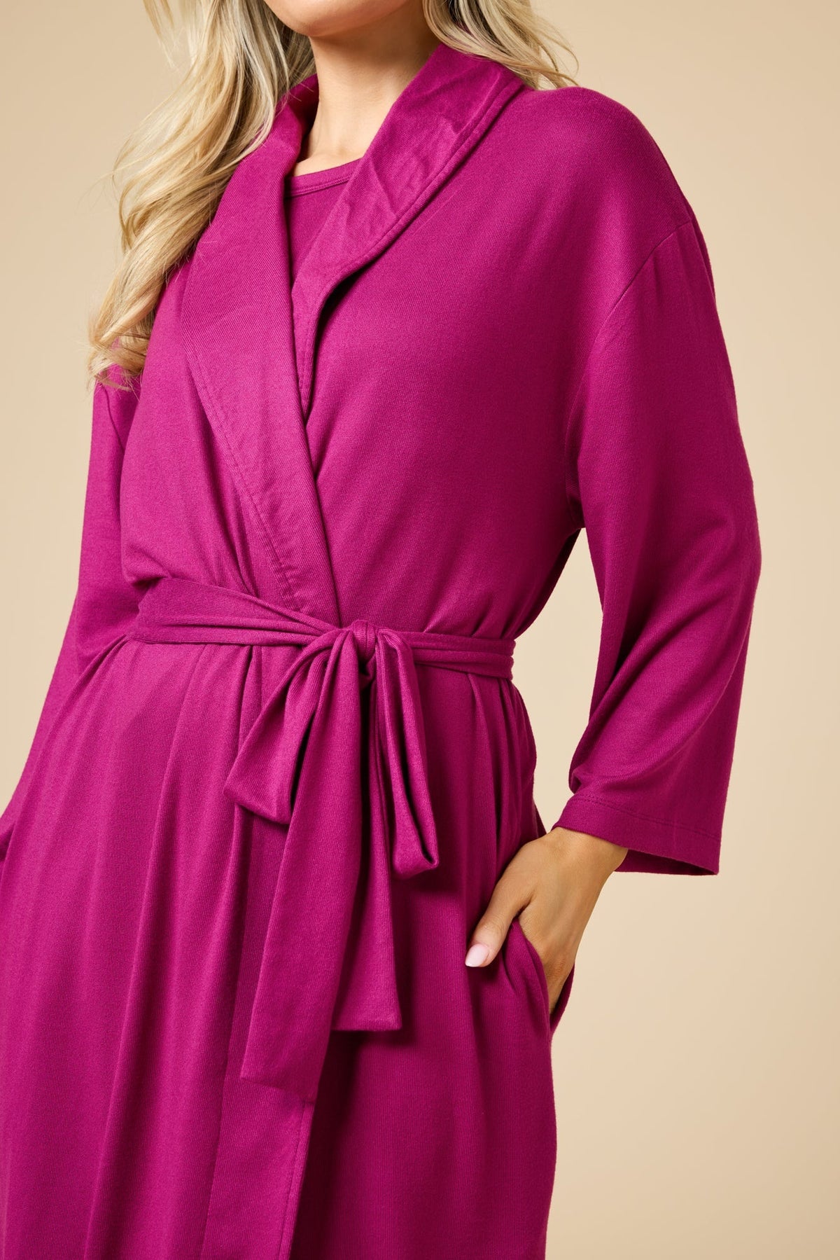 A woman wears a SOFTIES - DREAM SHAWL COLLAR ROBE in pink and white stripes, featuring a shawl collar, a tie waist, and three-quarter length sleeves.