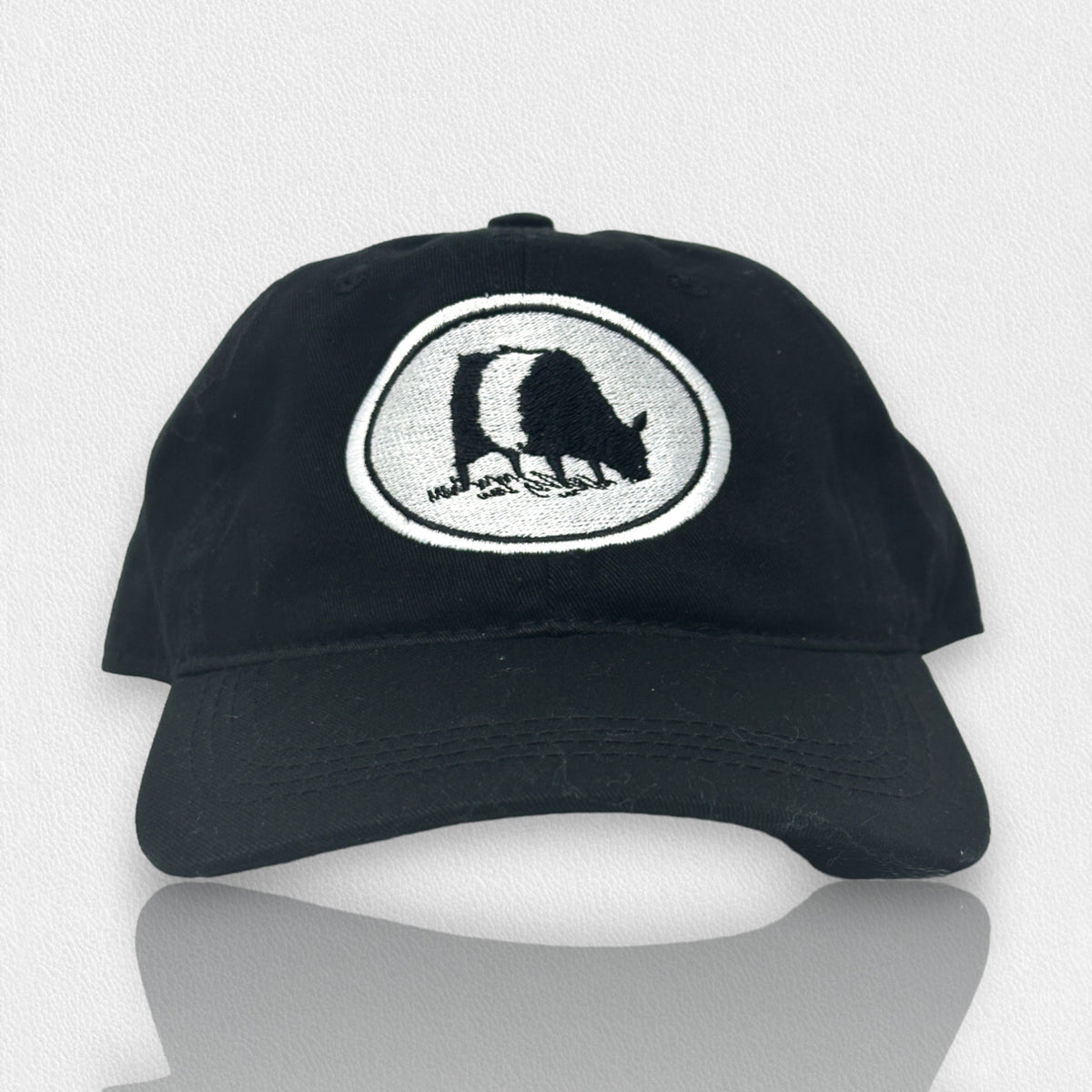 A black baseball cap with a white oval patch showing a black-and-white illustration of a bear walking, stitched on the front. The cap is displayed against a light, textured background.