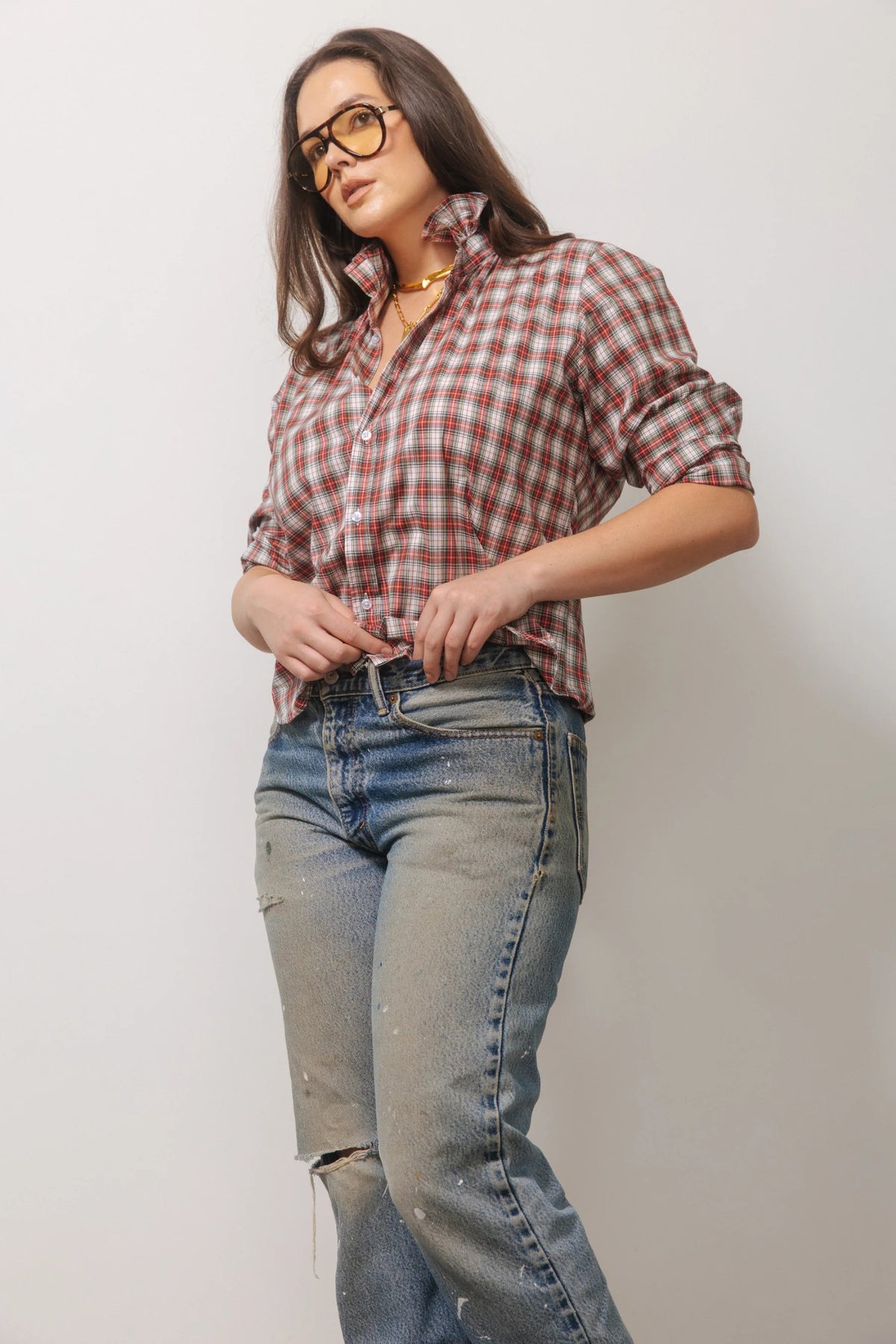 A person wears a relaxed-fit, long-sleeved red and white KMJ - QUARANTINA SHIRT IN HOLIDAY PLAID tucked into black high-waisted wide-leg trousers and black heeled sandals.
