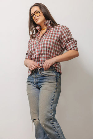 A person wears a relaxed-fit, long-sleeved red and white KMJ - QUARANTINA SHIRT IN HOLIDAY PLAID tucked into black high-waisted wide-leg trousers and black heeled sandals.