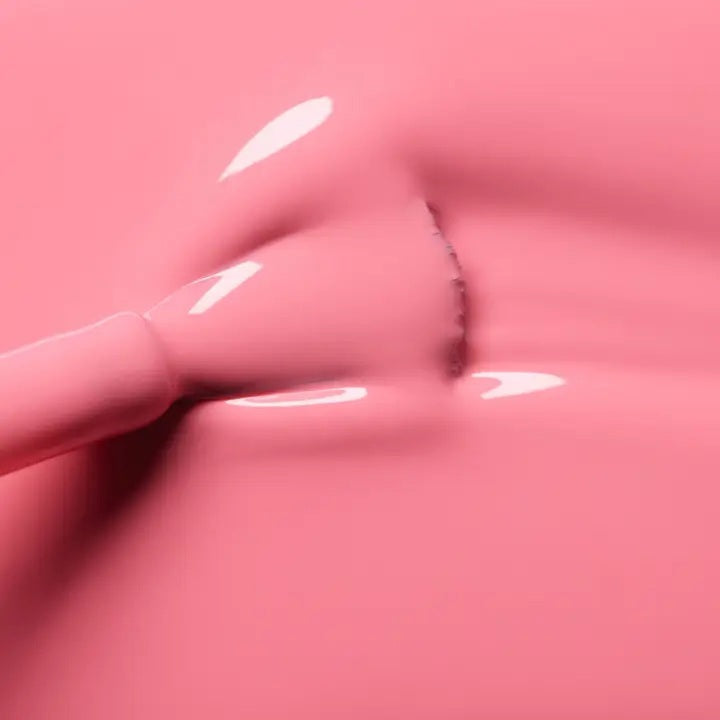 A hand with short, neatly manicured nails painted with MANUCURIST - GREEN™ Nail Polish in Pink Paradise by MANUCURIST INC rests on a cream-colored knitted fabric.