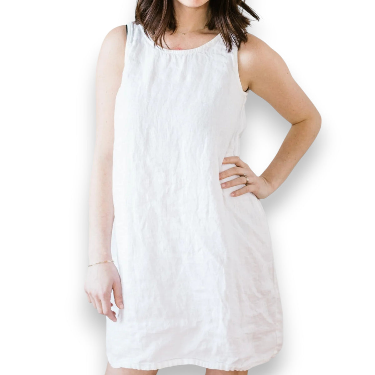 The CP SHADES - JESS SLEEVELESS DRESS, an A-line linen dress, hangs on a white clothes hanger against a light-colored wall. The dress features a round neckline and a minimalist design, with its slightly wrinkled texture adding to its charm. This eco-friendly piece by CP SHADES showcases solar-powered production at its finest.