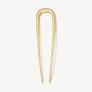 The MACHETE - MIDI FRENCH HAIR PIN IN GOLD by MACHETE is a handcrafted, U-shaped hair accessory with two long, pointed prongs, standing vertically against a plain white background to highlight its elegant simplicity.