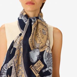 A woman, her face partially visible from the nose down, wears a sleeveless cream top and the INOUI EDITIONS - OCTOPUS SCARF IN NAVY by INOUI, featuring intricate hand-printed designs and text elegantly tied around her neck.
