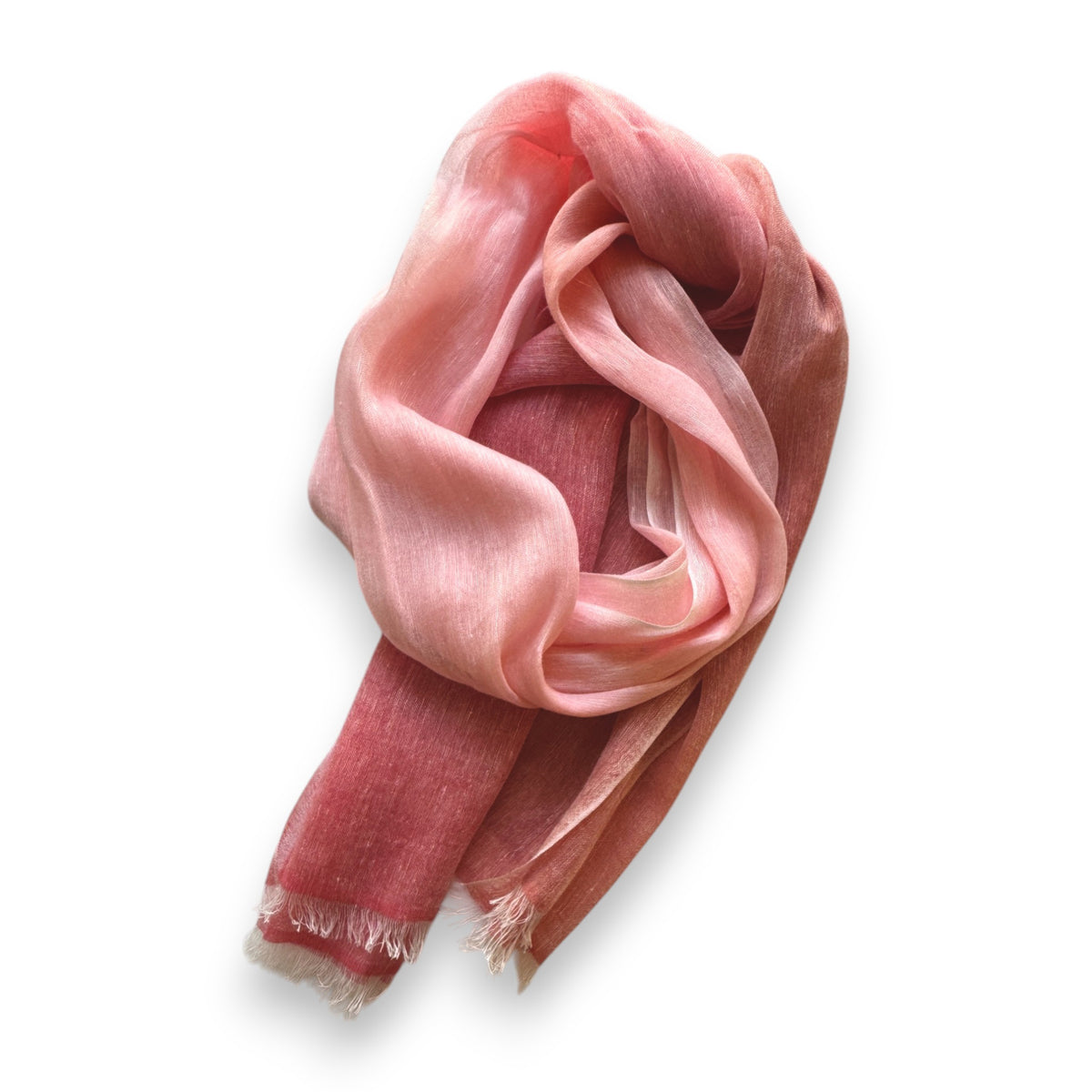 The BAJRA Hand Dyed Linen Blend Scarf in Peony Blush Ombre displays delicate Nepalese charm with its soft, lightweight fabric and gradient from deep red to soft pink, artistically draped on a plain white background. Its handmade fringed edges add to the elegance.