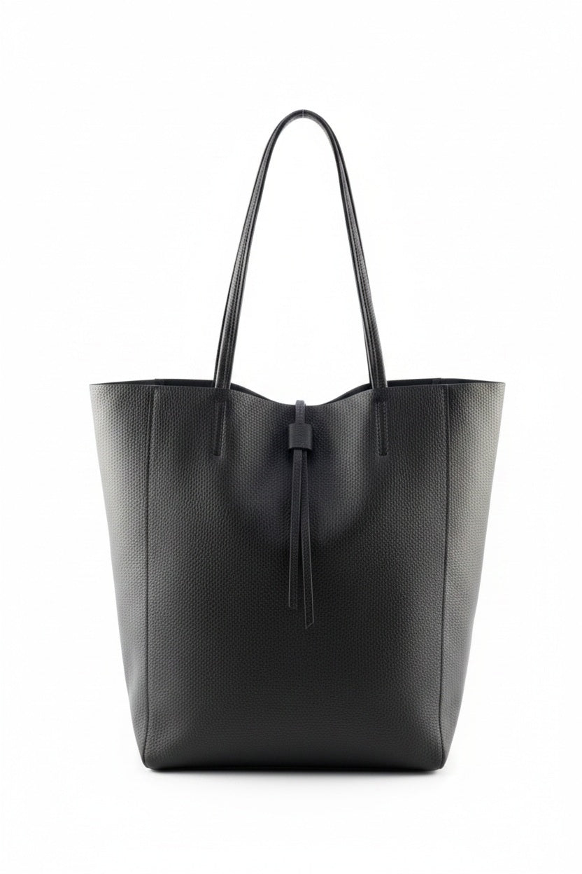 The LEATHER TOTE BAG IN BLACK by JIJOU CAPRI, featuring double handles and a simple tie closure, is crafted from Italian leather and stands upright against a white background—ideal for carrying your daily essentials.