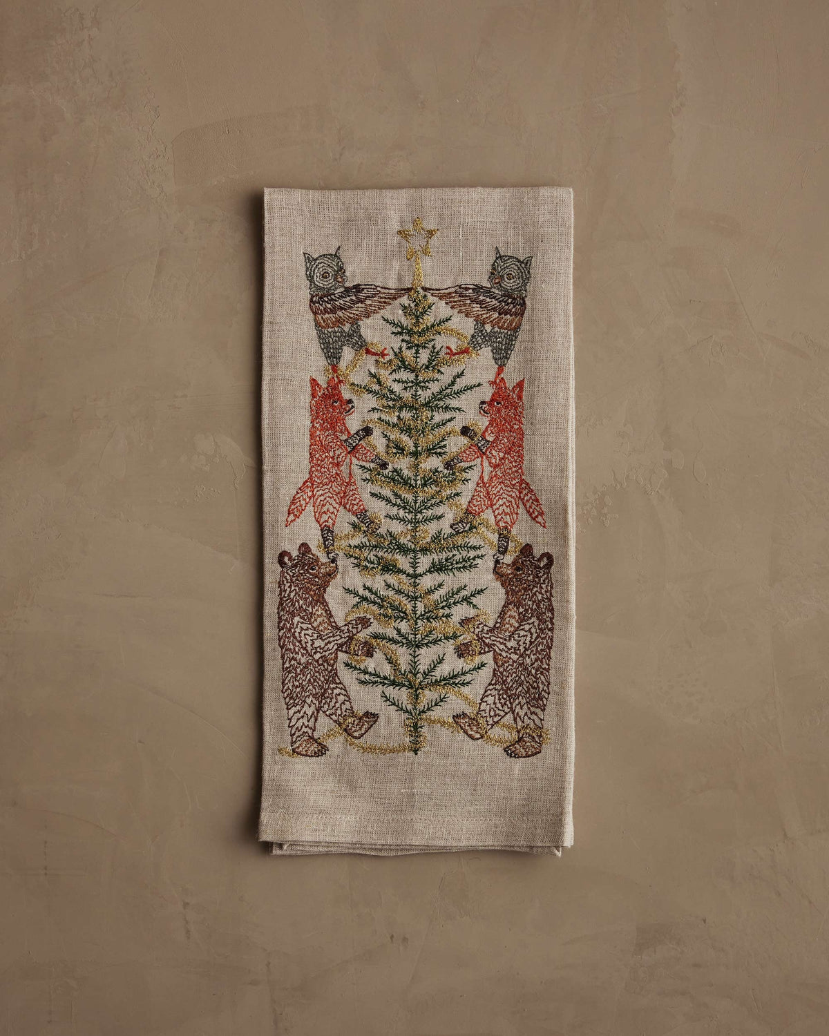 TINSEL TREE LINEN TEA TOWEL by CORAL & TUSK featuring embroidered owls, foxes, and bears decorating a tinsel tree for holiday decor.
