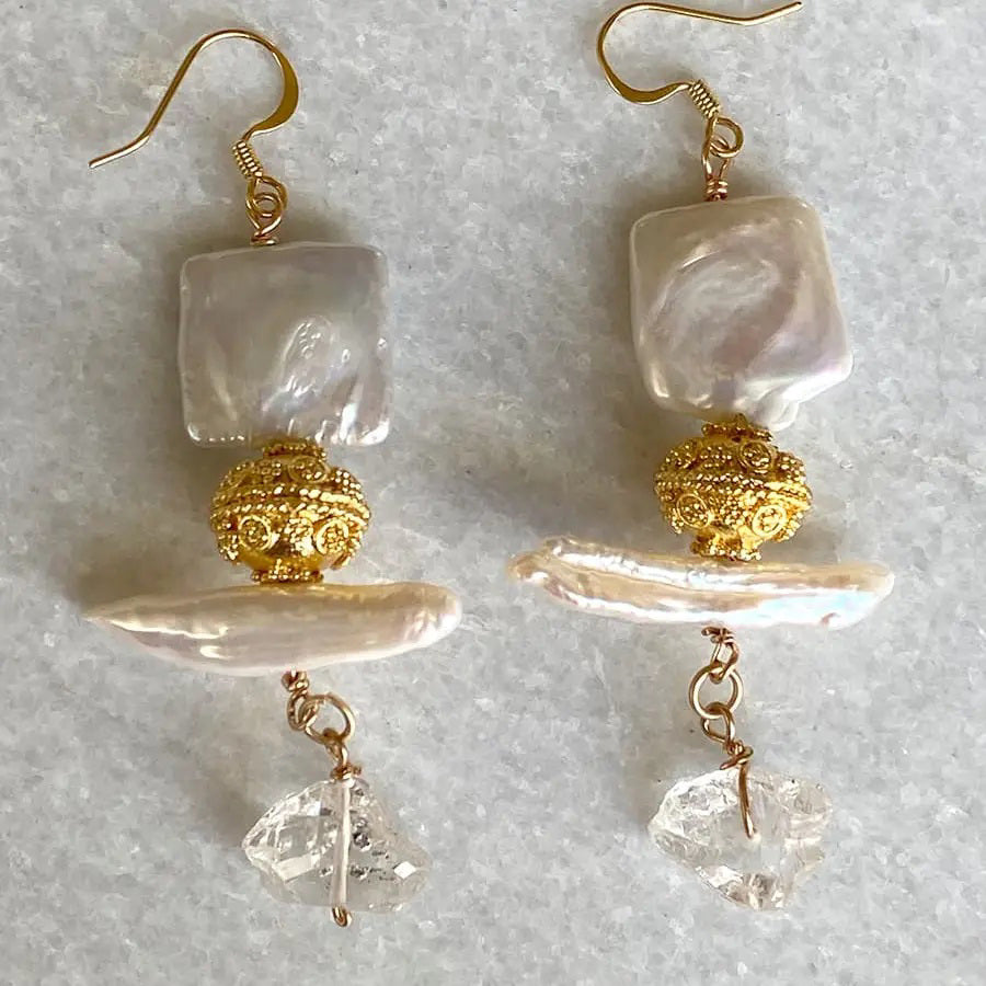 The BITTERSWEET DESIGNS - HERKIMER PEARL EARRINGS by BITTERSWEET DESIGNS feature square mother-of-pearl, ornate gold beads, biwa pearls, and raw crystal drops on gold wire hooks, shown on a light textured background.